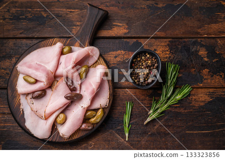 Italian cured meat slices spalla with olives and rosemary on wooden serving board forming a practical background for culinary advertising. 133323856