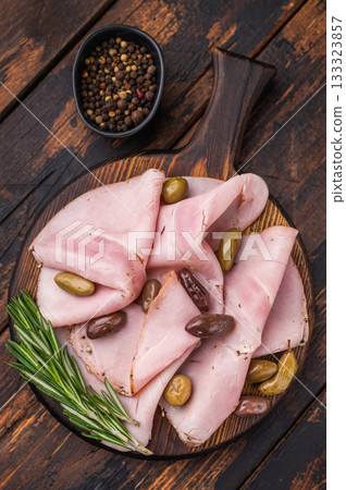 Italian cured meat slices spalla with olives and rosemary on wooden serving board forming a practical background for culinary advertising. Italian cured meat slices spalla with olives and rosemary on wooden serving board forming a practical background for culinary advertising. 133323857