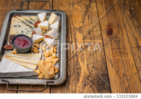Selection of creamy Brie soft Camembert blue Roquefort and aged Parmesan served with nuts on a textured wooden background. Selection of creamy Brie soft Camembert blue Roquefort and aged Parmesan served with nuts on a textured wooden background. 133323884