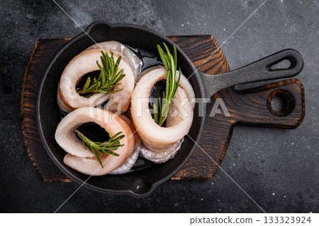 Ready for cooking Raw Pollock fish fillets in pan with herbs. black background. top view Ready for cooking Raw Pollock fish fillets in pan with herbs. black background. top view 133323924