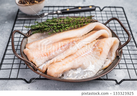 Raw Hake fish fillet in steel tray with herbs. grey background. top view Raw Hake fish fillet in steel tray with herbs. grey background. top view 133323925