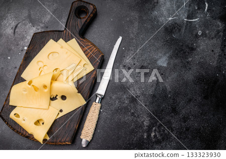 Swiss emmental cheese slices on wooden cutting board. black background. top view 133323930