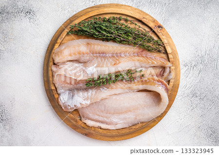 Fresh Raw Hake fish fillets, whitefish meat on a wooden board with herbs. white background. top view 133323945