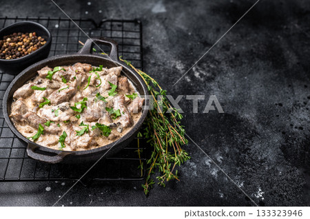 Creamy beef stroganoff with fresh greenery in a skillet. black background. top view Creamy beef stroganoff with fresh greenery in a skillet. black background. top view 133323946