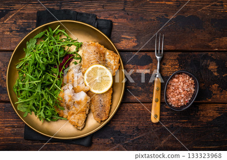 Roasted Pollock fish fillet on a plate with salad. wooden background. top view 133323968