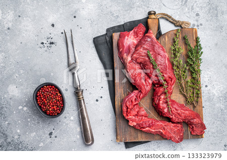 Uncooked Beef Skirt Steak, also name Machete steak, raw meat on cutting board. grey background. top view Uncooked Beef Skirt Steak, also name Machete steak, raw meat on cutting board. grey background. top view 133323979