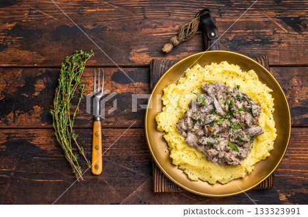 Beef Stroganoff over mashed potatoes with creamy sauce in a plate. wooden background. top view 133323991