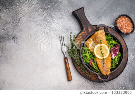 Fried Haddock fish fillet in a pan. grey background. top view Fried Haddock fish fillet in a pan. grey background. top view 133323993