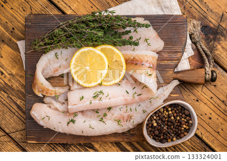 Haddock sea fish fillets, raw whitefish on a wooden board ready for cooking. wooden background. top view Haddock sea fish fillets, raw whitefish on a wooden board ready for cooking. wooden background. top view 133324001