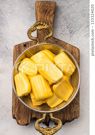 Sweet, golden jackfruit pods (bulbs) in a traditional metal bowl with a fork. Exotic tropical snack or dessert with copy space Sweet, golden jackfruit pods (bulbs) in a traditional metal bowl with a fork. Exotic tropical snack or dessert with copy space 133324020