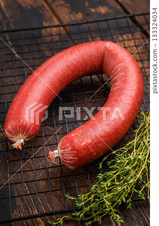 Whole raw Turkish sucuk (sujuk) on a cooling rack with thyme. Spicy dry-cured sausage on a rustic wooden background. Whole raw Turkish sucuk (sujuk) on a cooling rack with thyme. Spicy dry-cured sausage on a rustic wooden background. 133324034