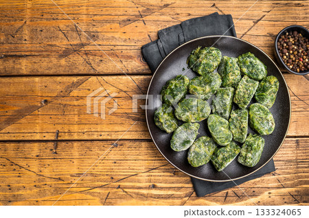 Raw, nutritious frozen spinach blocks on a dark plate, ready for thawing and cooking. Traditional rustic food photography. Raw, nutritious frozen spinach blocks on a dark plate, ready for thawing and cooking. Traditional rustic food photography. 133324065