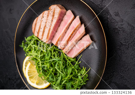 Succulent grilled tuna steak, showcasing vibrant color and rich taste, perfect for summer barbecues and elegant dinners. black background. top view Succulent grilled tuna steak, showcasing vibrant color and rich taste, perfect for summer barbecues and elegant dinners. black background. top view 133324136