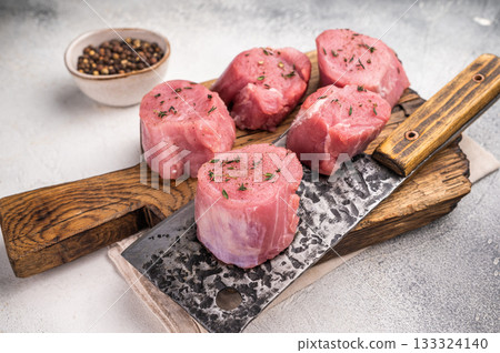 Juicy uncooked pork medallion, raw loin meat a versatile choice for stir fries or savory roasts in any cuisine. white background. top view Juicy uncooked pork medallion, raw loin meat a versatile choice for stir fries or savory roasts in any cuisine. white background. top view 133324140