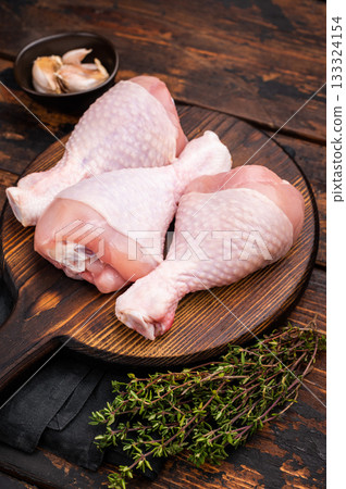 Uncooked poultry drumsticks, raw chicken legs ideal for your favorite recipes, waiting to be seasoned and cooked to perfection. wooden background. top view 133324154