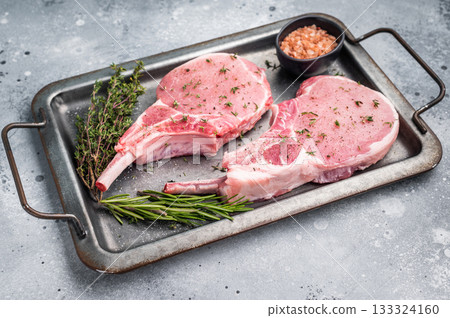 Stunning uncooked pork Tomahawk chop steak, promising tenderness and flavor in every bite when grilled or roasted. grey background. top view Stunning uncooked pork Tomahawk chop steak, promising tenderness and flavor in every bite when grilled or roasted. grey background. top view 133324160