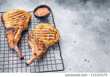 Juicy grilled pork Tomahawk chop, perfectly seared and bursting with flavor, ideal for a hearty feast. grey background. top view Juicy grilled pork Tomahawk chop, perfectly seared and bursting with flavor, ideal for a hearty feast. grey background. top view 133324175