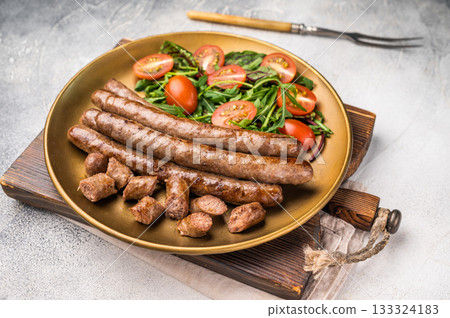 Close up of perfectly charred grilled sausage with salad, ideal for adding flavor to your favorite dishes or sandwiches. white background. top view 133324183