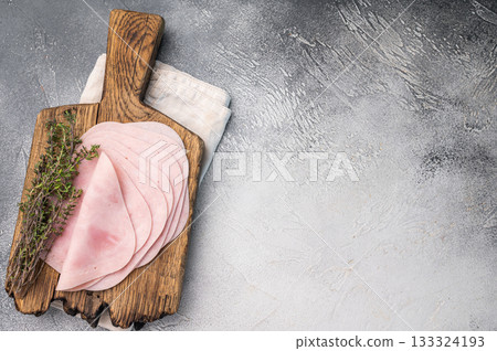 Delicious slices of cured ham on a wooden platter, ideal for entertaining and adding flavor to your dishes. white background. top view 133324193