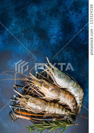 Uncooked rosenbergii fresh water shrimp ready for preparation, perfect for chefs looking to create exquisite seafood dishes. blue background. top view Uncooked rosenbergii fresh water shrimp ready for preparation, perfect for chefs looking to create exquisite seafood dishes. blue background. top view 133324199