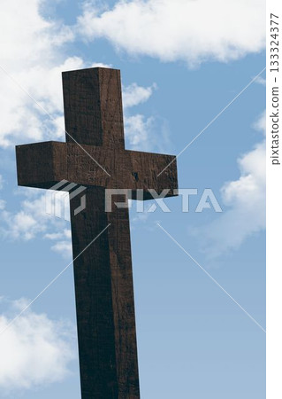 Large rough-hewn wooden cross is rising against flat design blue sky with scattered cumulus clouds 133324377