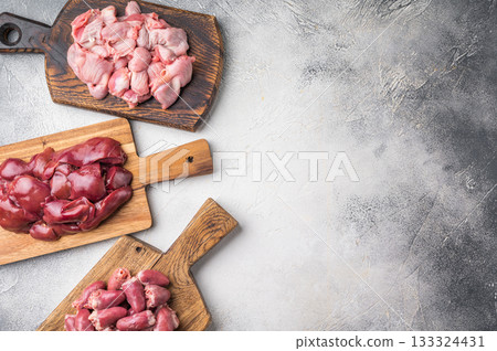 Assorted raw giblets including hearts, liver, and gizzards on vintage wooden boards, organic poultry cooking concept. Assorted raw giblets including hearts, liver, and gizzards on vintage wooden boards, organic poultry cooking concept. 133324431