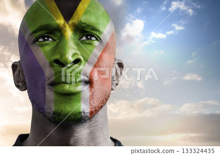 Portrait is showing man looking upward under sunrise sky, featuring South African flag face paint 133324435
