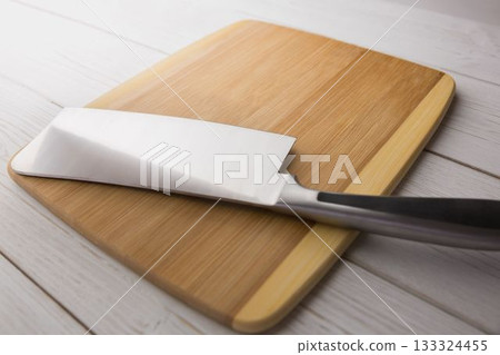 Knife and chopping board on wooden floor 133324455