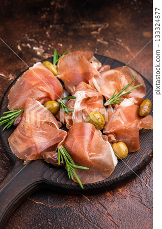 Gourmet Italian Prosciutto with fresh rosemary on a dark round plate. Gourmet Italian Prosciutto with fresh rosemary on a dark round plate. 133324877