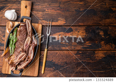 Grilled beef short ribs (Flanken/Galbi) with rosemary and garlic. Served on a wooden background with copy space. Grilled beef short ribs (Flanken/Galbi) with rosemary and garlic. Served on a wooden background with copy space. 133324889