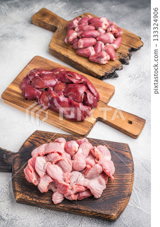 Assorted raw giblets including hearts, liver, and gizzards on vintage wooden boards, organic poultry cooking concept. Assorted raw giblets including hearts, liver, and gizzards on vintage wooden boards, organic poultry cooking concept. 133324906