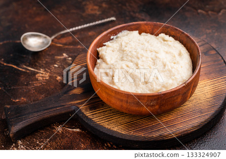 Overhead shot of rich white condiment (aioli or horseradish) in a bowl on a dark textured wood surface. Gourmet serving style. Overhead shot of rich white condiment (aioli or horseradish) in a bowl on a dark textured wood surface. Gourmet serving style. 133324907