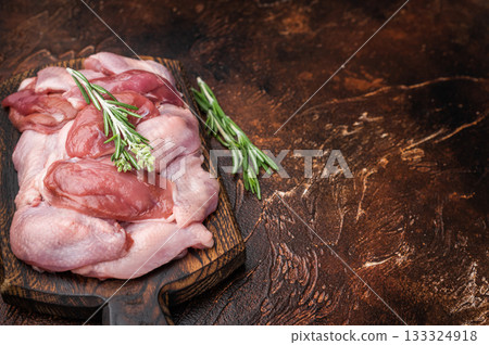 Butcher cut: Uncooked quail fillets and fresh rosemary on a dark wooden board. High-protein healthy food. 133324918