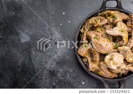 Cooked stew from poultry gizzards with herbs in cast iron pan on dark stone background perfect for rustic food photography and menu design. 133324921