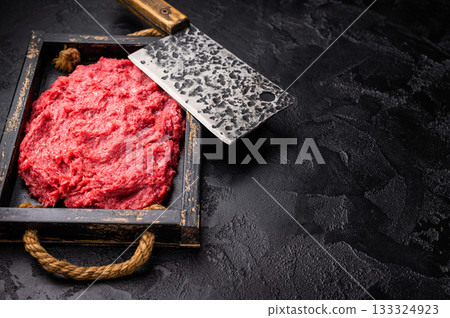 Wild game meat: Heap of raw ground hare rabbit on a textured black wooden tray. Ingredient for savory recipes. Wild game meat: Heap of raw ground hare rabbit on a textured black wooden tray. Ingredient for savory recipes. 133324923