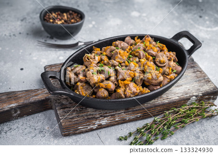 Fried chicken hearts with carrot and herbs in cast iron pan on gray concrete background perfect for food photography. Fried chicken hearts with carrot and herbs in cast iron pan on gray concrete background perfect for food photography. 133324930