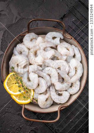 Uncooked prawns shrimps ready for gourmet cooking. Dark, moody shot with citrus and herbs. Negative space for text. Uncooked prawns shrimps ready for gourmet cooking. Dark, moody shot with citrus and herbs. Negative space for text. 133324944