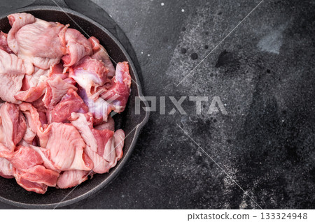 Fresh poultry duck offal in a black skillet, minimalist dark background highlights the raw product 133324948