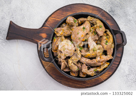 Cooked chicken gizzards with herbs in cast iron pan on white background perfect for rustic food photography and recipe design. Cooked chicken gizzards with herbs in cast iron pan on white background perfect for rustic food photography and recipe design. 133325002