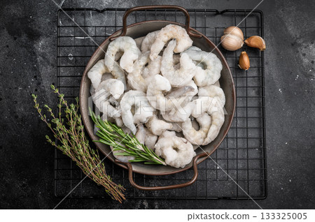 Raw frozen shellfish with rosemary on a black surface. High-quality healthy food ingredient with ample copy space. 133325005