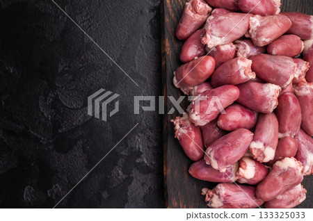 Raw chicken hearts with rosemary on dark wooden board and black stone background, fresh poultry offal ready for cooking. Raw chicken hearts with rosemary on dark wooden board and black stone background, fresh poultry offal ready for cooking. 133325033