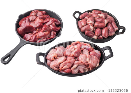 Raw chicken liver, gizzards, and hearts in black cast iron pans on white background. Fresh poultry offal cooking ingredients closeup. Raw chicken liver, gizzards, and hearts in black cast iron pans on white background. Fresh poultry offal cooking ingredients closeup. 133325056