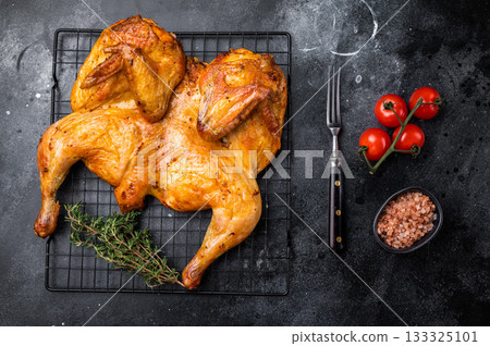 Roasted Spatchcock chicken with herbs and spices, poultry meat on steel rack. black background. top view Roasted Spatchcock chicken with herbs and spices, poultry meat on steel rack. black background. top view 133325101