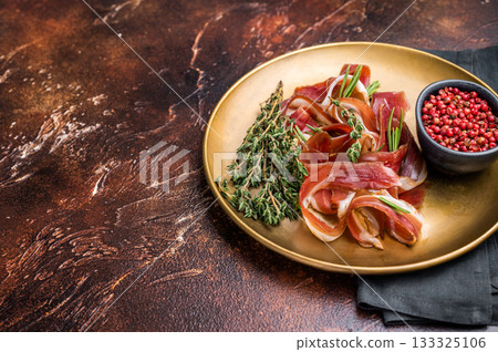Cured duck fillet meat slices, magret smoked poultry on a plate. brown background. top view 133325106