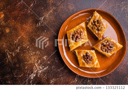 Delicious Honey Walnut Baklava on plate. brown background. top view Delicious Honey Walnut Baklava on plate. brown background. top view 133325112