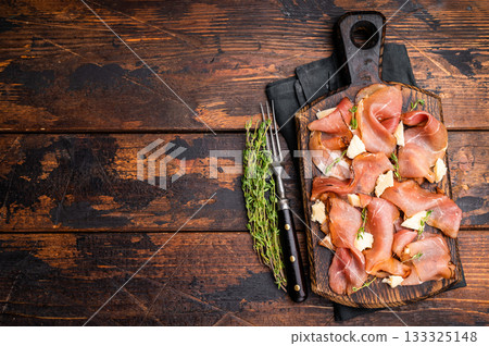 Italian Prosciutto parma ham with herbs and parmesan cheese on wooden board. wooden background. top view Italian Prosciutto parma ham with herbs and parmesan cheese on wooden board. wooden background. top view 133325148
