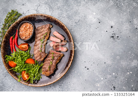 BBQ Grilled skirt or machete Steak, beef meat on a plate with salad. grey background. top view 133325164