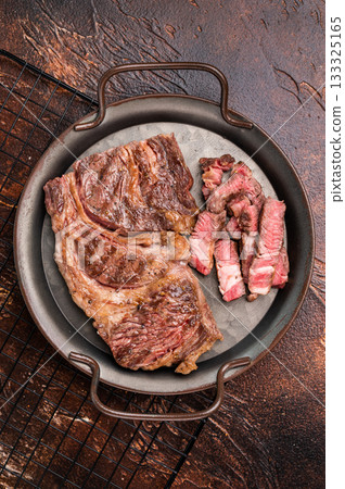 BBQ fried and sliced Chuck eye roll steak in a steel tray, prime beef meat. brown background. top view 133325165