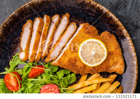 Roast viennese schnitzel steak, breaded meat with salad and french fry on a plate. black background. top view Roast viennese schnitzel steak, breaded meat with salad and french fry on a plate. black background. top view 133325171