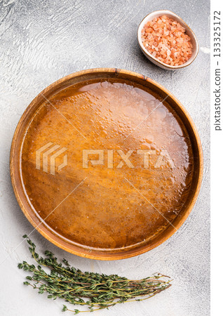 Chicken Bouillon or Broth in a wooden plate. white background. top view 133325172